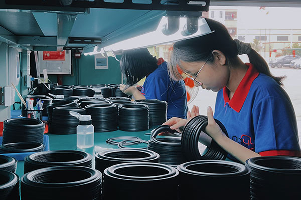 Workers inspecting rubber speaker surrounds on the production line